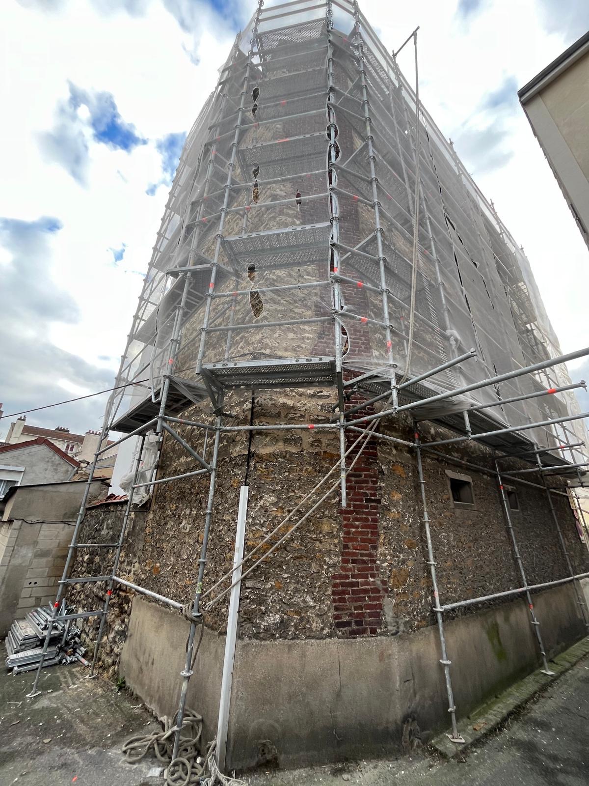 Échafaudage enveloppant l’angle d’un bâtiment en pierre