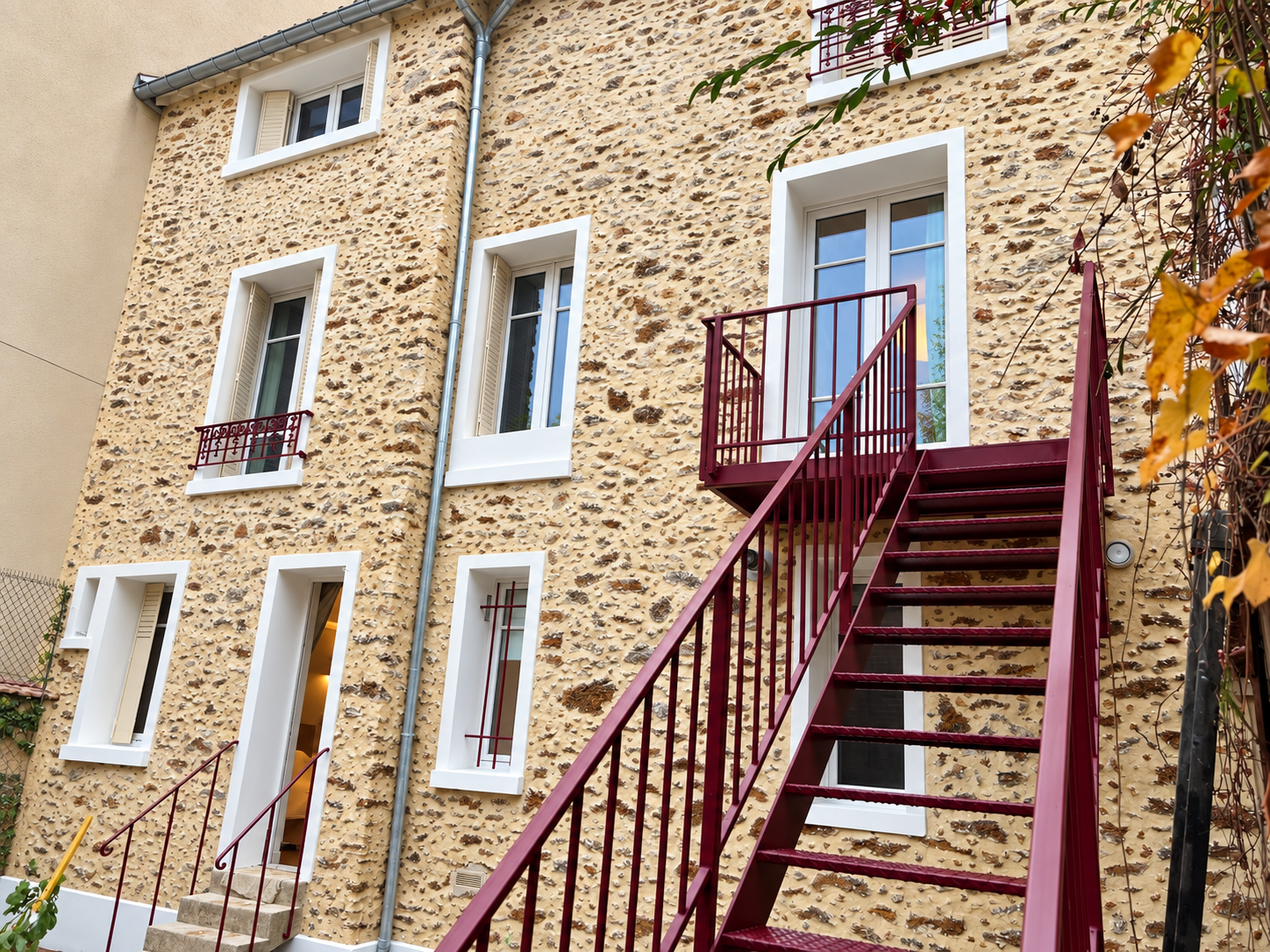 Façade en pierre et escalier extérieur bordeaux